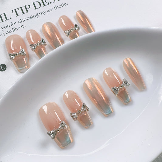 Set of pink nail tips with decorative bows on a white dish